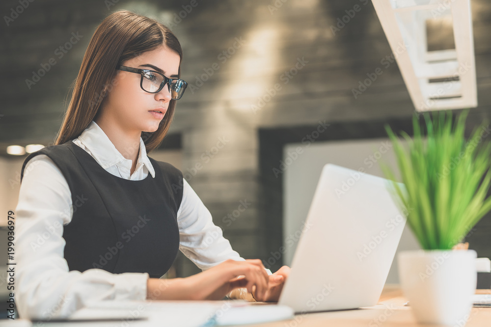 The beautiful woman with a laptop sitting at the desktop The beautiful woman with a laptop sitting at the desktop
