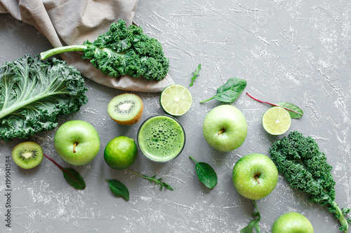 Healthy green smoothie with ripe green fruits, kale and spinach on gray background, top view