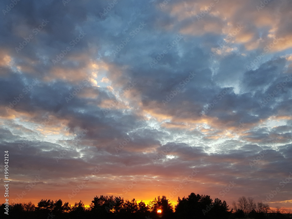 Fototapeta premium Fiery orange sunset colorful and speckled clouds.