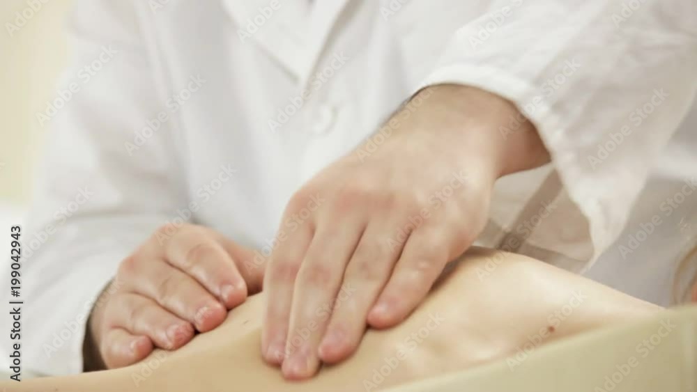 Doctor masseur doing shoulder massage, a young girl lying on a couch