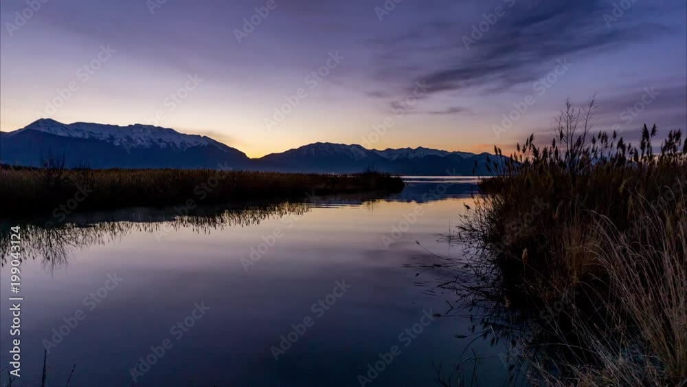 Time lapse from dark to the early minutes of a the sunrise where a river empties into a like and the mountains in the background Time lapse from dark to the early minutes of a the sunrise where a river empties into a like and the mountains in the background