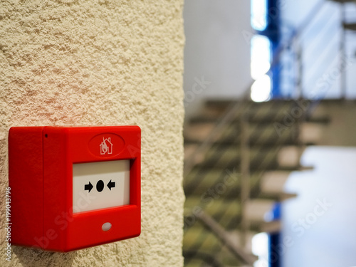 Close-up of the red manual Fire Call Point mounted or installed in the landing on a yellow wall. High-quality macro photography.