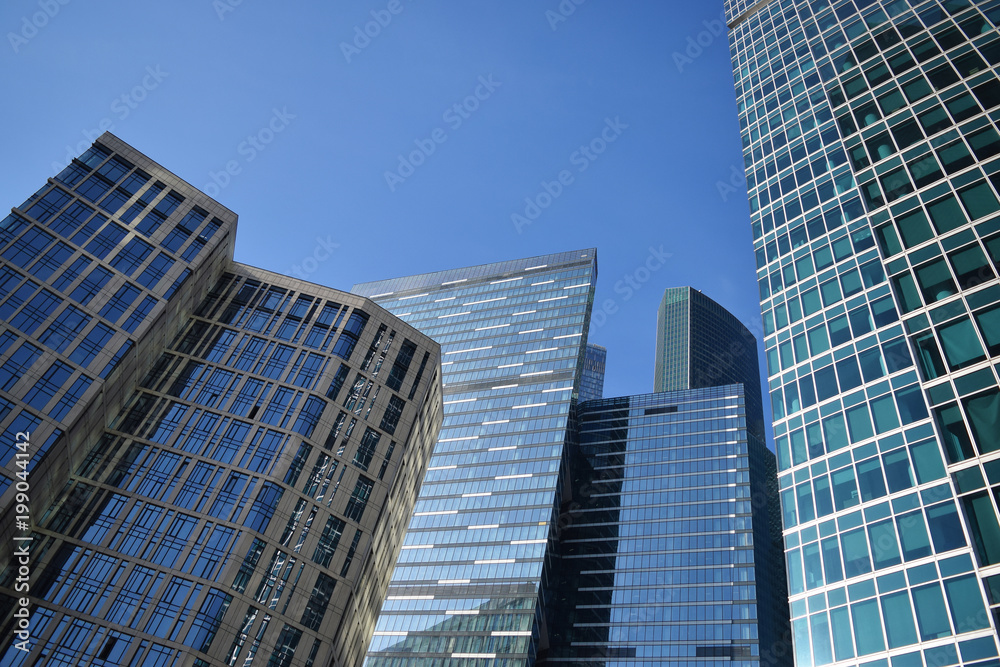 Low angle view of skyscrapers against blue sky on a sunny day. City landscape.