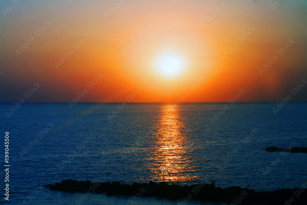 Beautiful sunset on the sea with shallow waves in summer hot evening poster background
