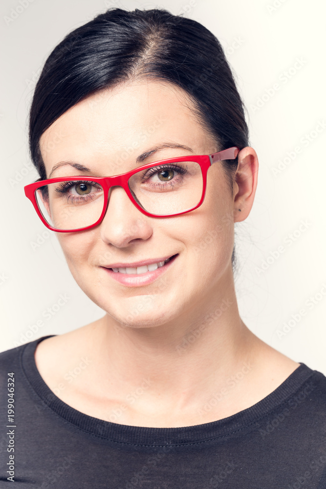 Portrait of a young woman with black hair and red glasses.