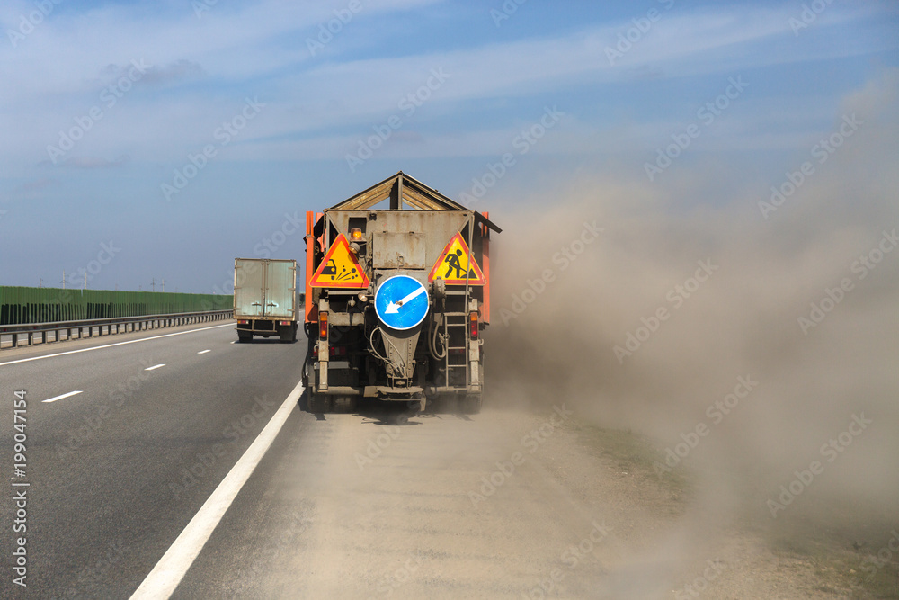 Cleaning asphalt on the road. Strong wind on the road and dust