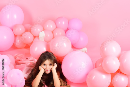 Little girl with long hair in pink balloons.