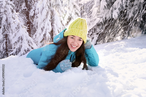 Beautiful happy woman lying on snow in countryside. Winter vacation