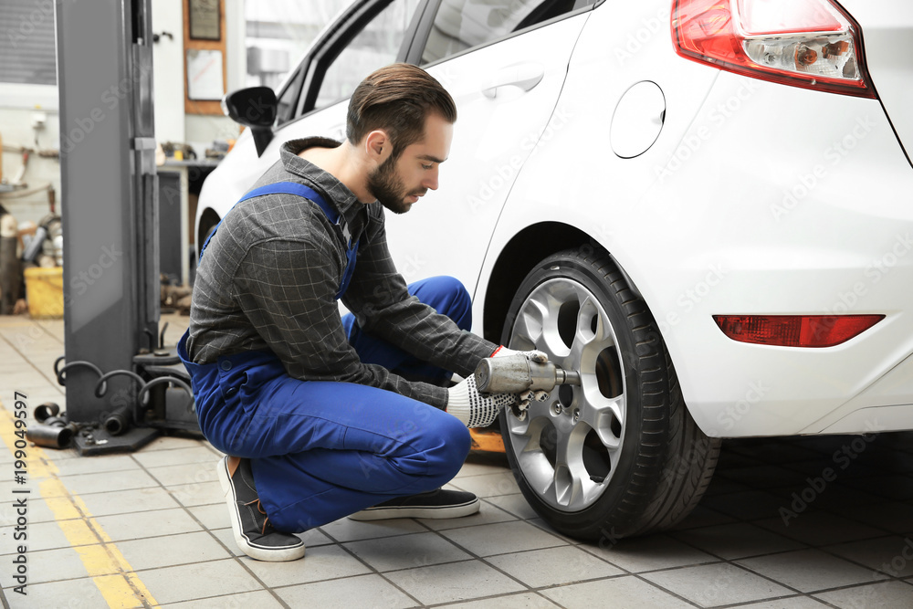 Young mechanic changing wheel at tire service Young mechanic changing wheel at tire service