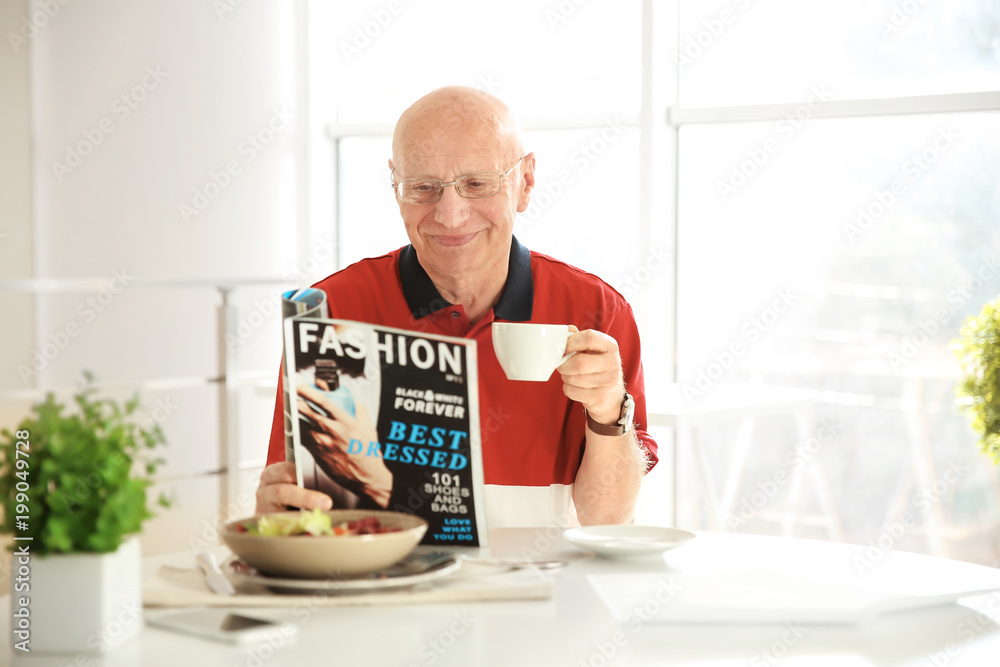 Elderly man reading magazine while having breakfast at home Elderly man reading magazine while having breakfast at home