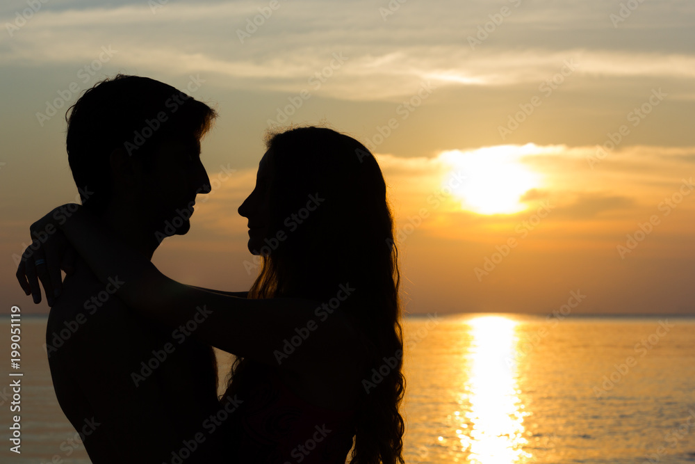 Lovely Valentine's Day scene of a young couple silhouettes hugging each other by the sea at fabulous sunset in the island of Koh Phangan, Thailand. Summer vacation, romantic travel destination concept