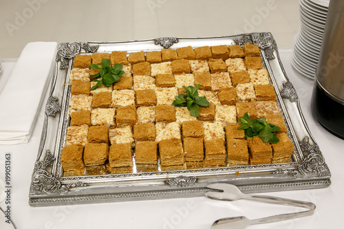 a lot of pieces of fresh honey cakes, on a iron tray. Event catering service, top view