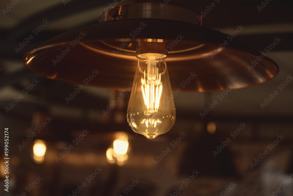 Beautiful retro luxury light lamp decor glowing from dark blurred background in a modern cafe Beautiful retro luxury light lamp decor glowing from dark blurred background in a modern cafe
