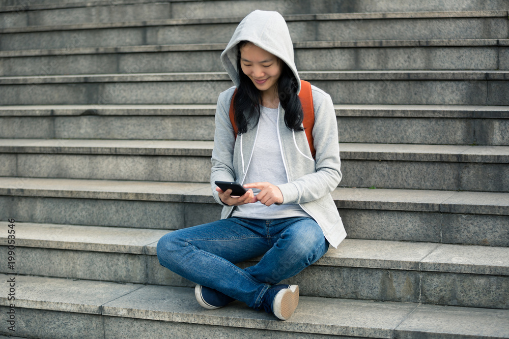 Woman using smartphone while sitting on city stairs