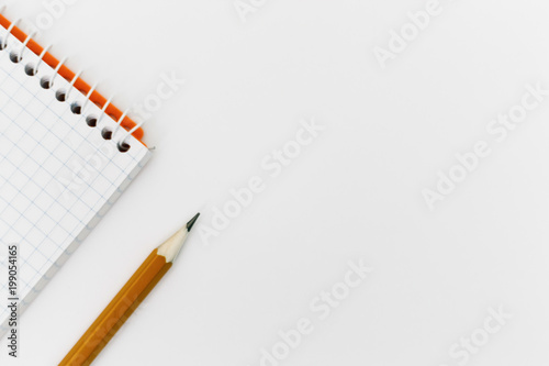Top view of an open spiral blank notepad with a pencil on a white table background