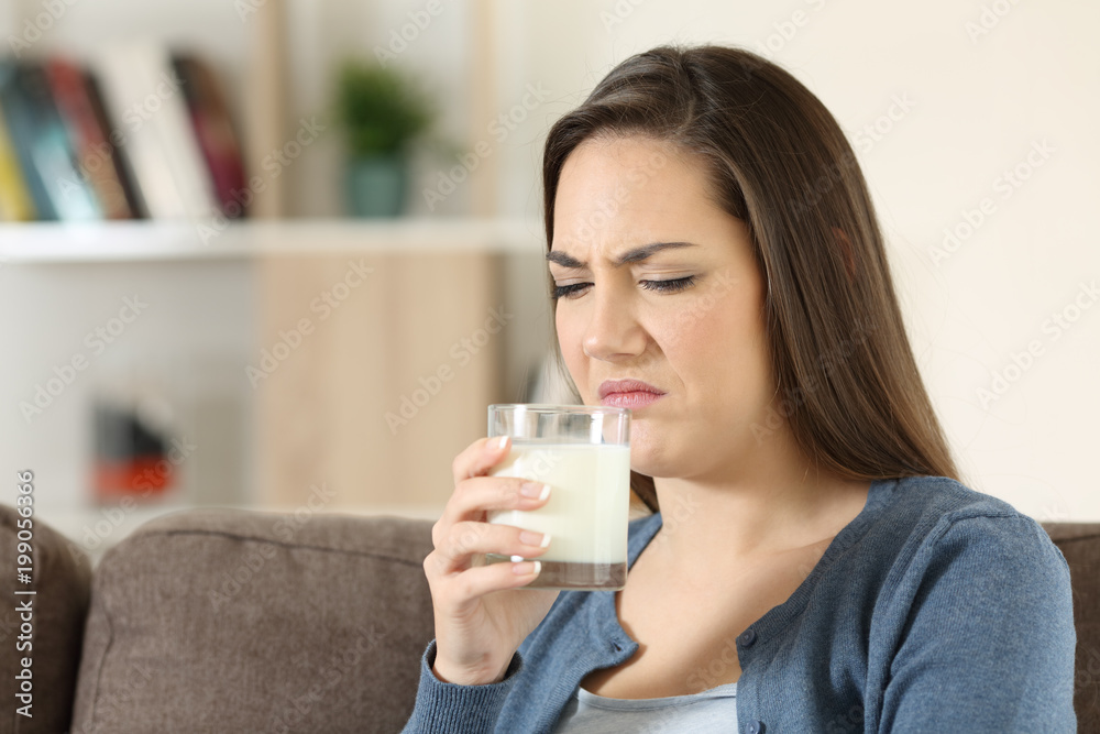 Woman disgusted tasing milk with bad flavor Woman disgusted tasing milk with bad flavor
