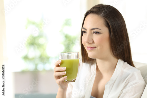 Relaxed woman holding a vegetable juice looking away