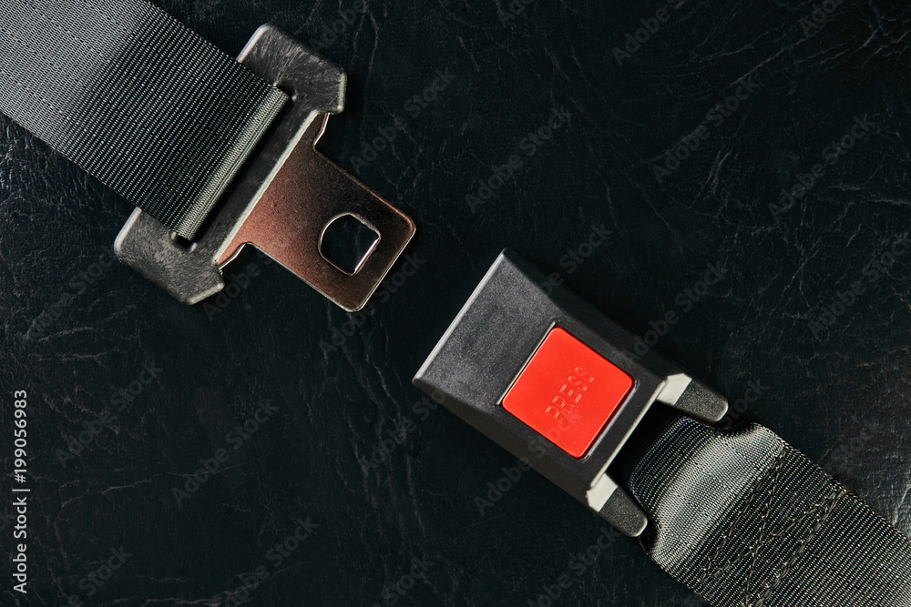 Opened seat belt on black leather background, close-up. Safety concept