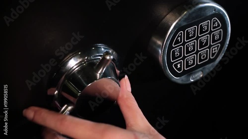 A hand opens a combination lock on a steel vault