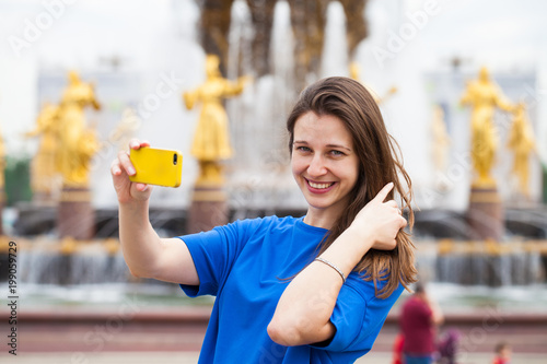 Smiling woman take a picture of herself with a smartphone. Selfie