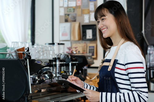 Young asian barista taking note  order  at coffee cafe counter with smiling face  food and drink business concept