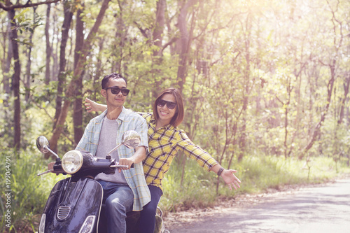 Beautiful young couple in helmets riding a scooter through forest. life style idea concept