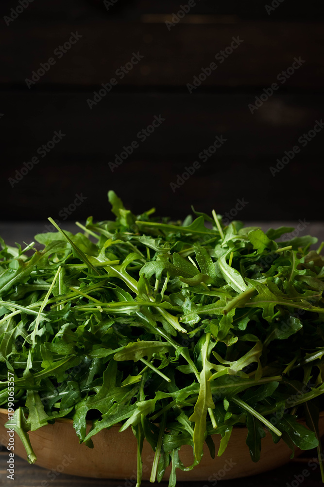 Fresh rucola with water droplets on a dark rustic background Fresh rucola with water droplets on a dark rustic background