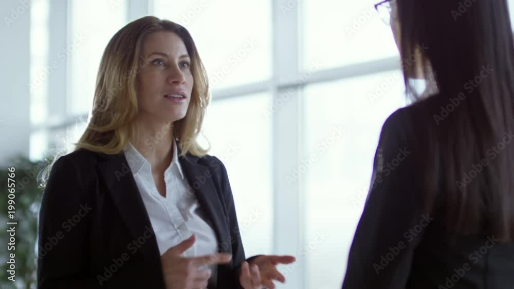 Medium shot of cheerful businesswoman in formal clothes gesturing and talking with young woman Medium shot of cheerful businesswoman in formal clothes gesturing and talking with young woman