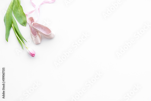 Ballet shoes near delicate flowers on white background top view copy space