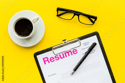 Recruitment. Select employees. Resume near coffee, glasses on yellow background top view