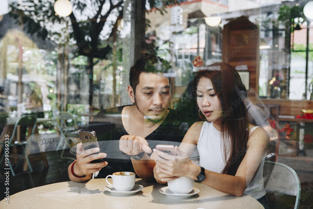 Couple using a phone at a cafe Couple using a phone at a cafe