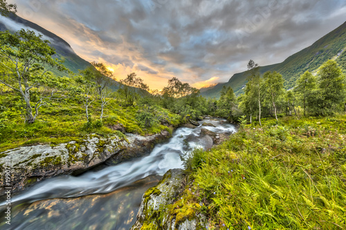 Sunset over small river through birch forest in Norway