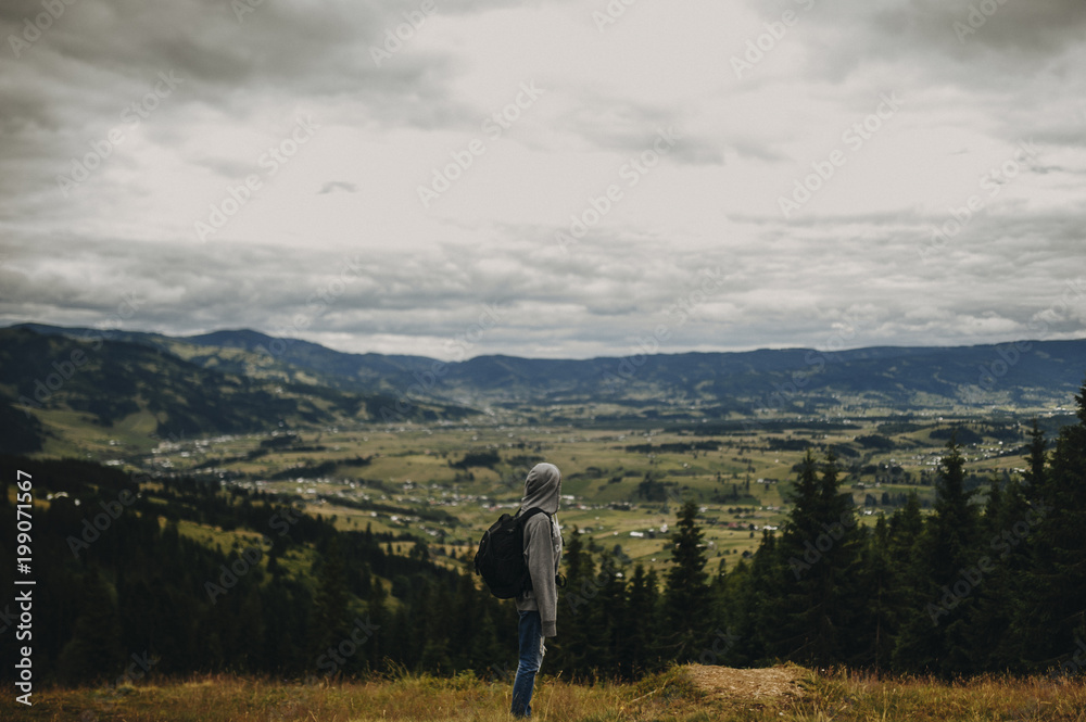 Woman carrying a sports backpack and look somewhere on the moutains.