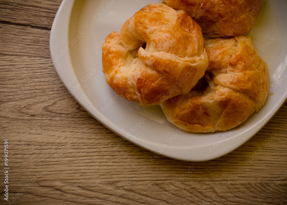 Croissants pastry on the wooden table. The croissants is a bread product made of a layered yeast-leavened dough with butter rolled and folded several times in succession, then rolled into a sheet. Croissants pastry on the wooden table. The croissants is a bread product made of a layered yeast-leavened dough with butter rolled and folded several times in succession, then rolled into a sheet.
