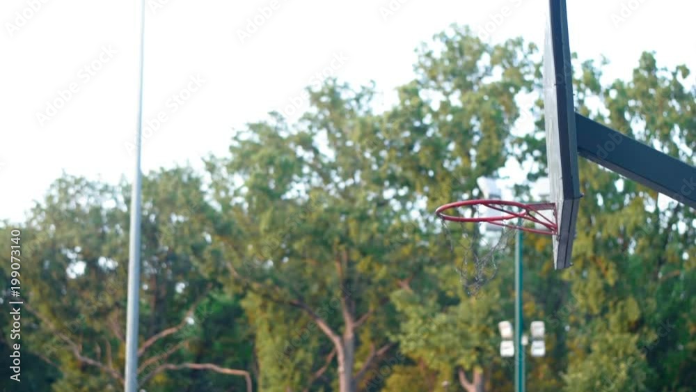 A player in streetball makes a slam dunk. Basketball training outdoors in the park. Healthy lifestyle. Video in full hd format