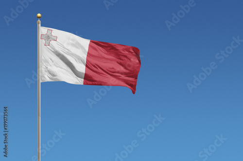 Flag of Malta in front of a clear blue sky