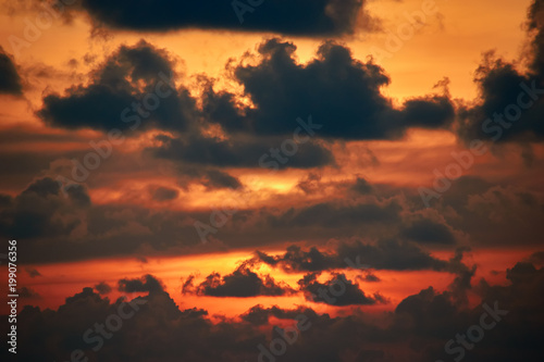 Sunset Clouds. Dramatic sunset in orange sunlight. Flaming sunset with light passing through the dark clouds. Landscape.