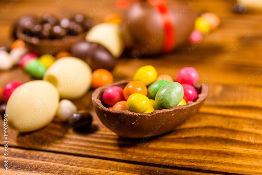 Chocolate easter eggs and multicolored candies on wooden table Chocolate easter eggs and multicolored candies on wooden table