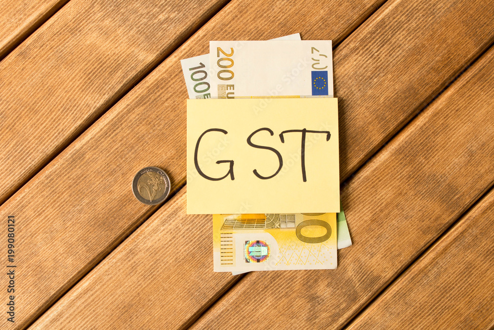 Goods and Services Tax . GST inscription with banknotes on wooden background Goods and Services Tax . GST inscription with banknotes on wooden background