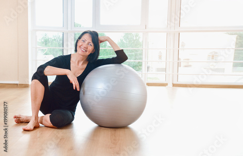 Happy senior woman resting after exercise with gray exercise ball photo