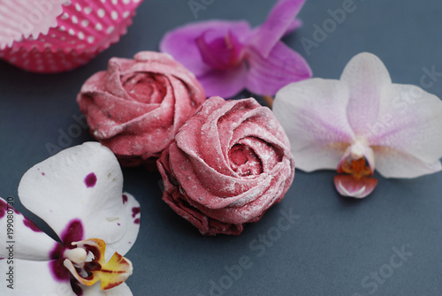 Fototapeta Naklejka Na Ścianę i Meble -  Sweet Pink Meringues and Cuup of Coffee on Blue Gray background with Orchid Flowers. Spring Background with copy space. Breakfast.