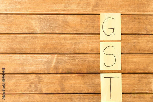  Goods and services and Tax . GST the inscription on the wooden background