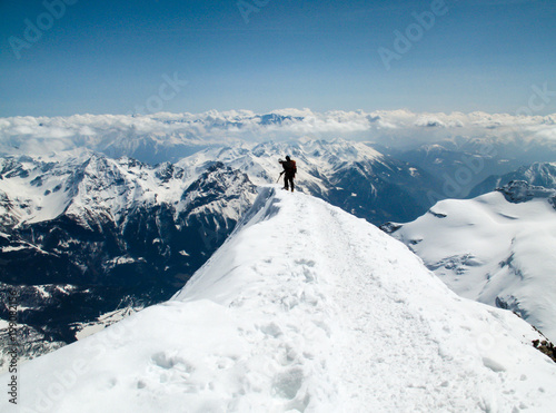 male back country ski mountaineer hiking along a narrow and exposed summit ridge of a high alpine peak © makasana photo