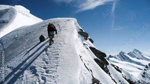 mountain guide and client on a steep north face slope heading towards the summit with a great view of the surrounding mountain landscape in the Alps near Grindelwald photo