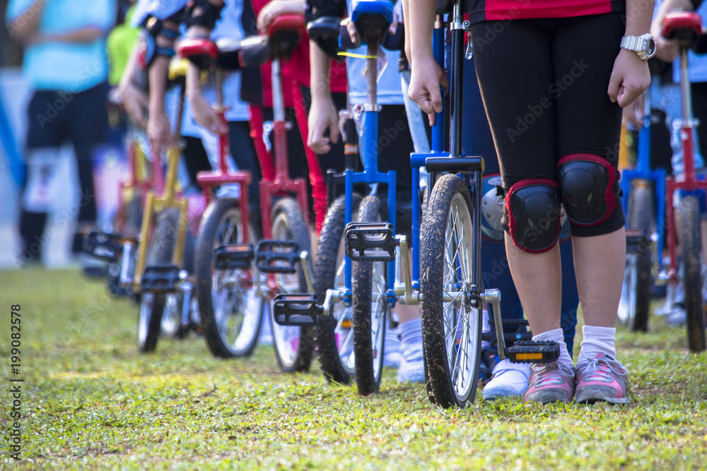 Fototapeta premium Colorful unicycles lined up in straight line awaiting respective turn for relay.
