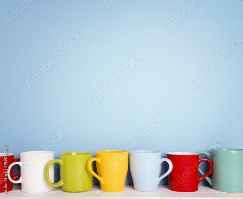 Colorful mugs on a blue background with copy space.