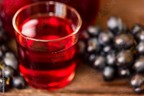 Red grape juice in glass and grapes close