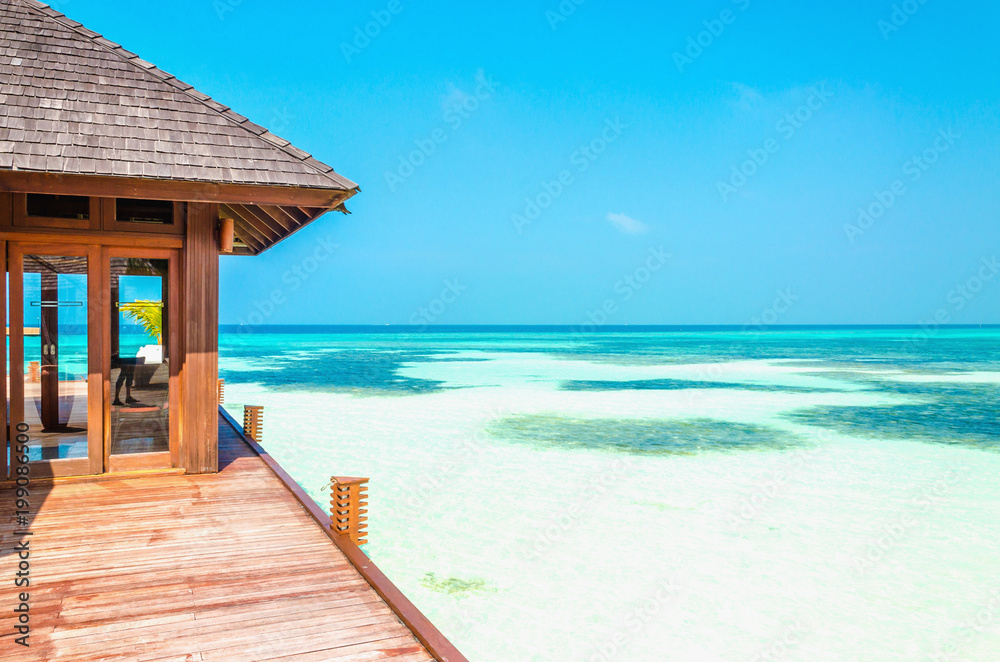 Luxury wooden house on stilts on the background of azure water and beautiful sunny sky