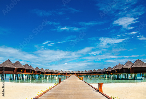 Beautiful exotic beach and wooden bridge to amazing exotic bungalows on turquoise water