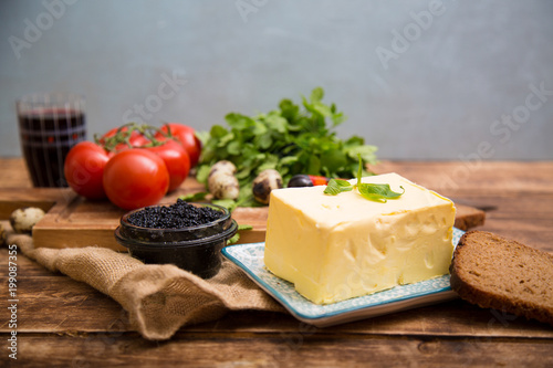 Natural food and ingredients, breakfast with butter, bread and black caviar on wooden background
